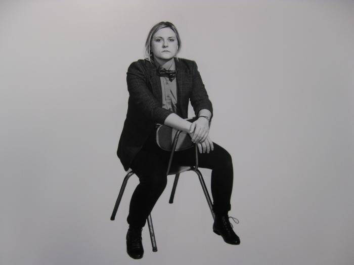 Photograph of a person sitting backwards in chair wearing a suit.